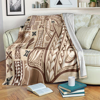 Beige tapa blanket with dark tribal pattern, laid across a striped couch