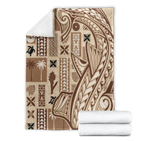 Beige tapa blanket with dark tribal pattern, folded beside rolled towels