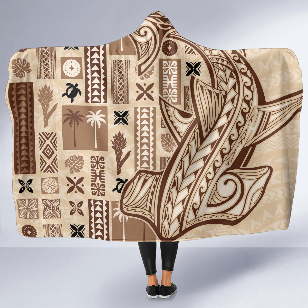 Beige hooded blanket with brown and black Polynesian tapa panel pattern.