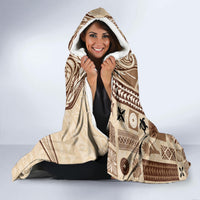 Beige and brown hooded blanket with tapa print and white fleece-lined hood.