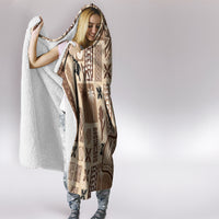Beige hooded blanket with brown tapa print and cozy white sherpa lining.