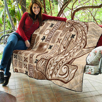 Beige quilt with dark brown tatau shield-like motif and patchwork panels, quilted.