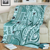 Teal tapa pattern blanket with large central bird-like figure, laid on a sofa