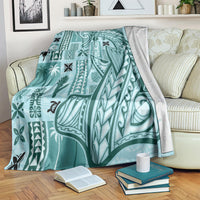 Teal tapa pattern blanket with tribal border, draped over a couch and chair
