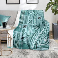 Teal tapa pattern blanket with geometric motifs, folded over the arm of a chair