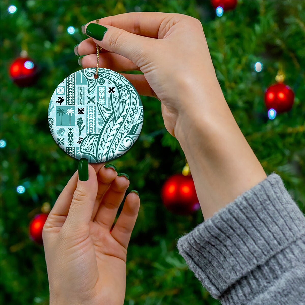 Teal circular tapa-pattern ceramic ornament held in hand, gold hanging chain