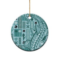Teal circular ceramic ornament with detailed tapa pattern, gold hanging loop on white