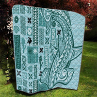 Teal quilt with geometric tapa blocks, swirling tribal motif, and black edge trim
