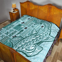 Teal quilt blanket on bed with stitched pattern and black-edged border