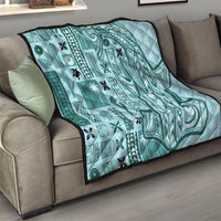 Teal tapa quilt on sofa with geometric swirls, patch motifs, and black border