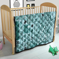 Teal tapa quilt on wooden baby bed, quilted geometric and swirl designs with black trim
