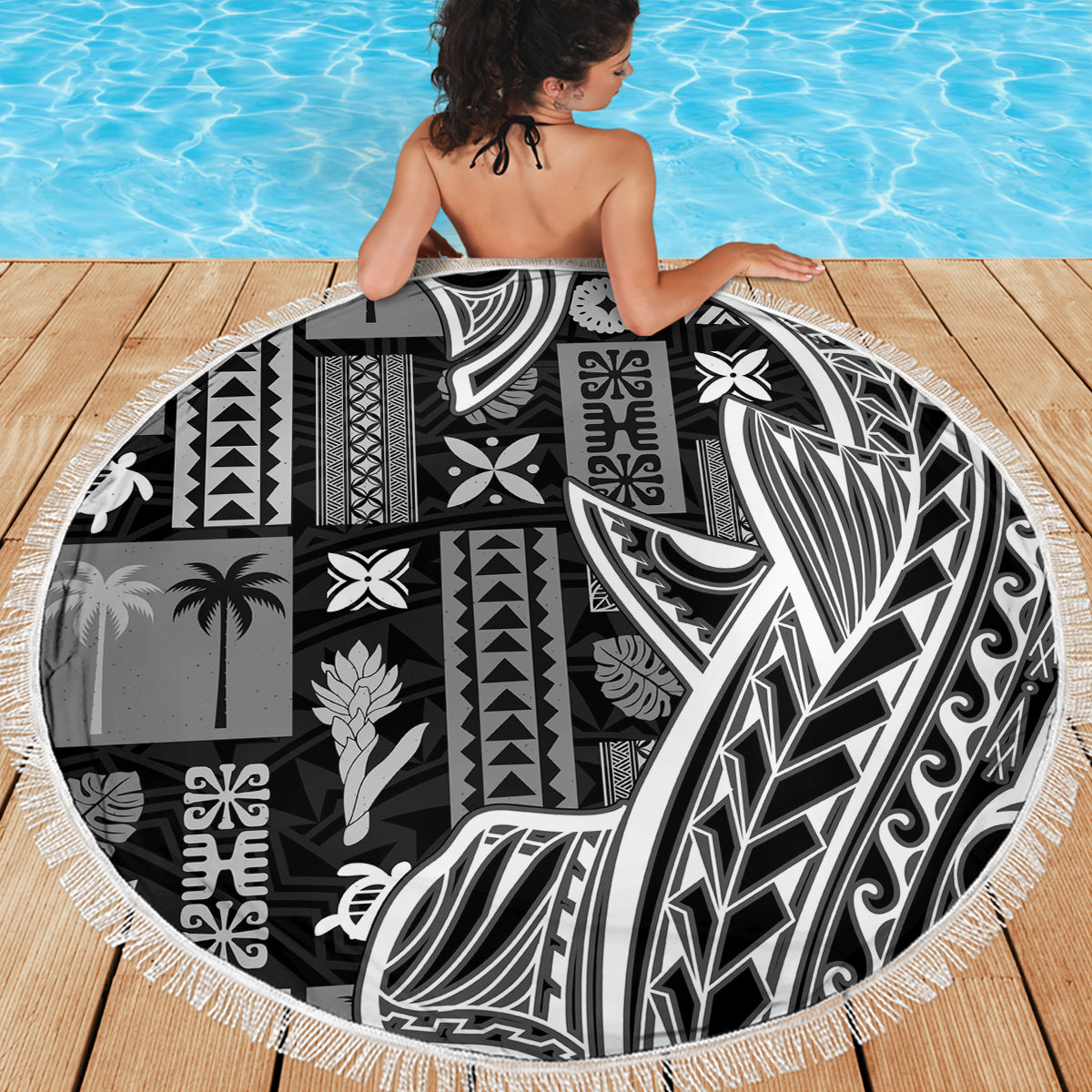 Round beach blanket with bold black-and-white tapa/tatau motifs and white fringe border.