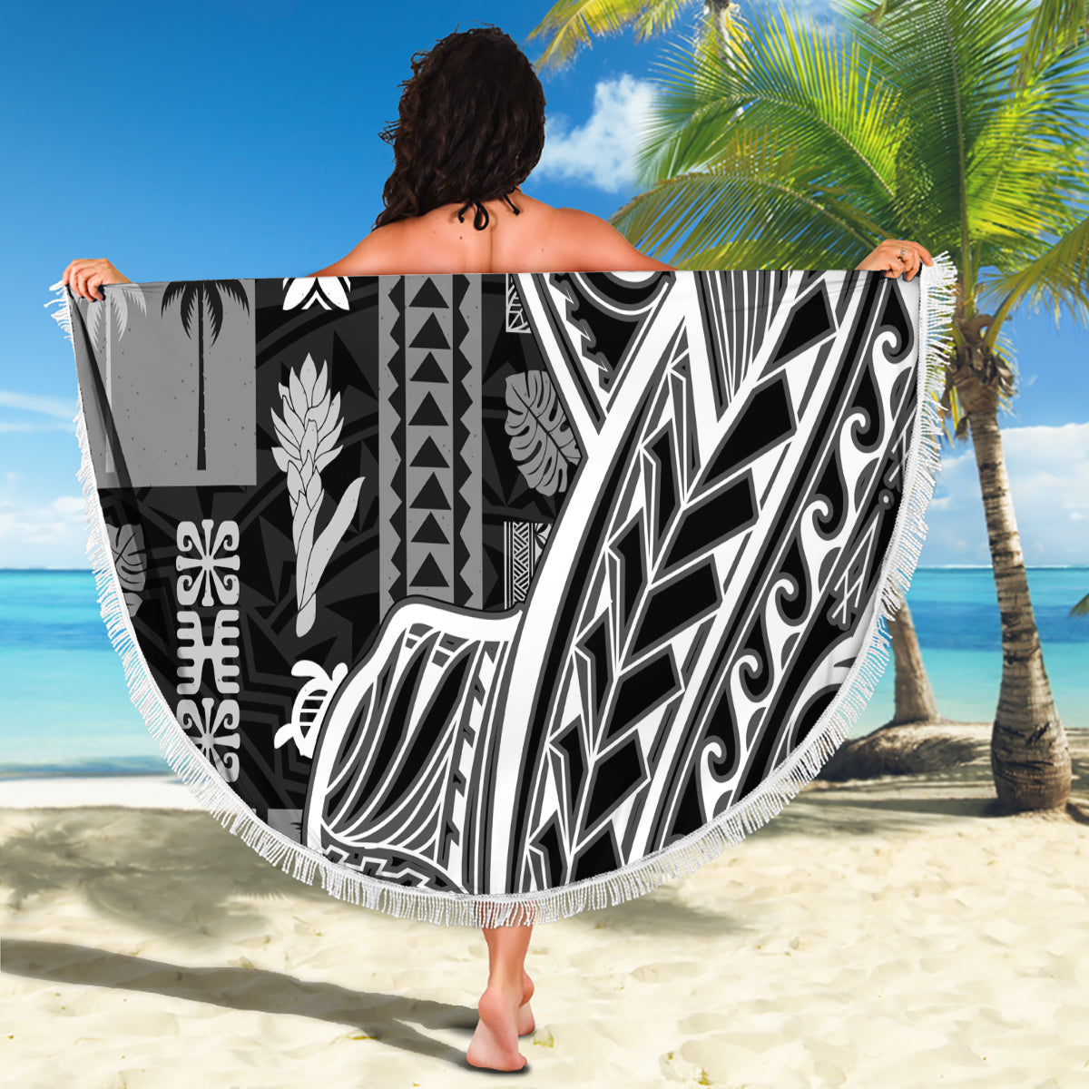 Round beach blanket with black-and-white tapa/tatau motifs and white fringe border.