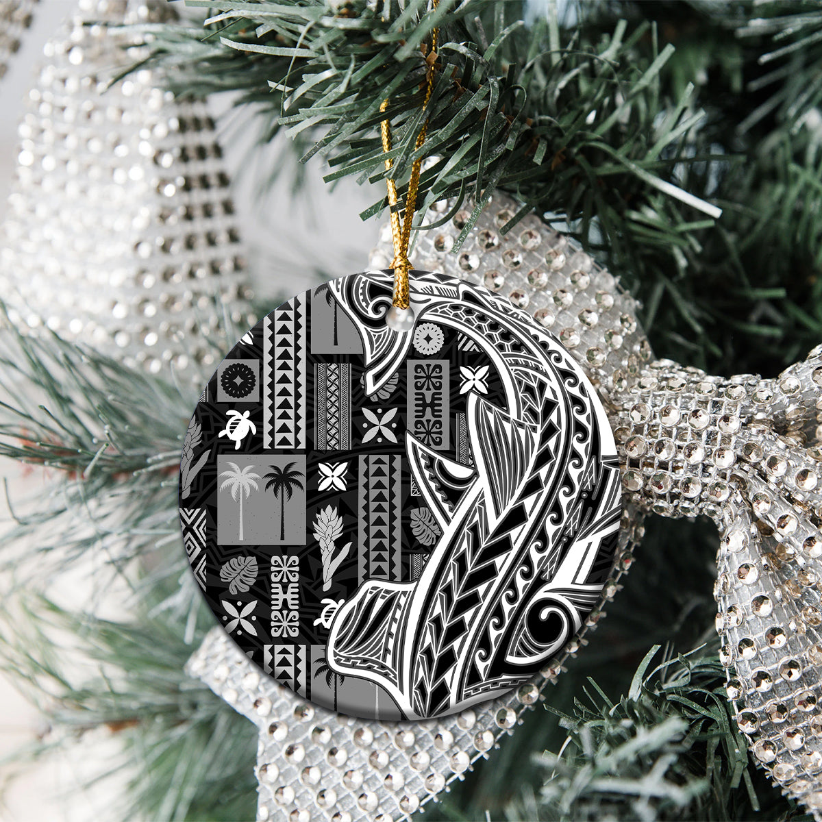 Round black and white tapa ceramic ornament hanging on a Christmas tree