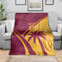 Maroon and yellow tropical blanket laid on a gray sofa with palm tree and “07”