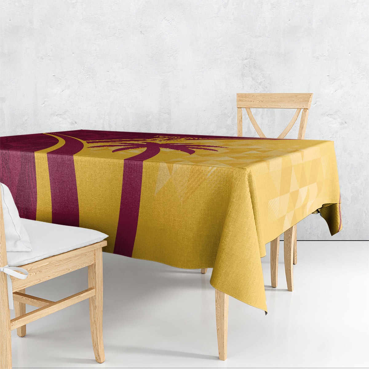 Maroon and yellow tablecloth with tropical palm motif and geometric pattern, draped on table.