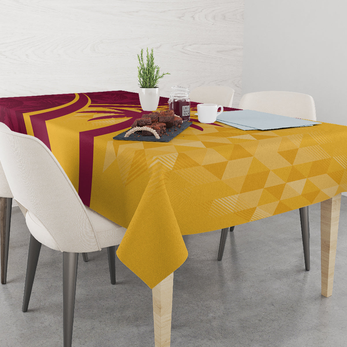 Maroon and yellow tropical cricket tablecloth on dining table with geometric pattern.