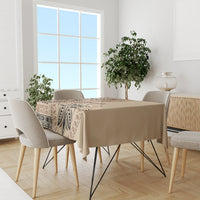 Beige tablecloth with dark brown geometric border and leaf motif, on dining table with chairs