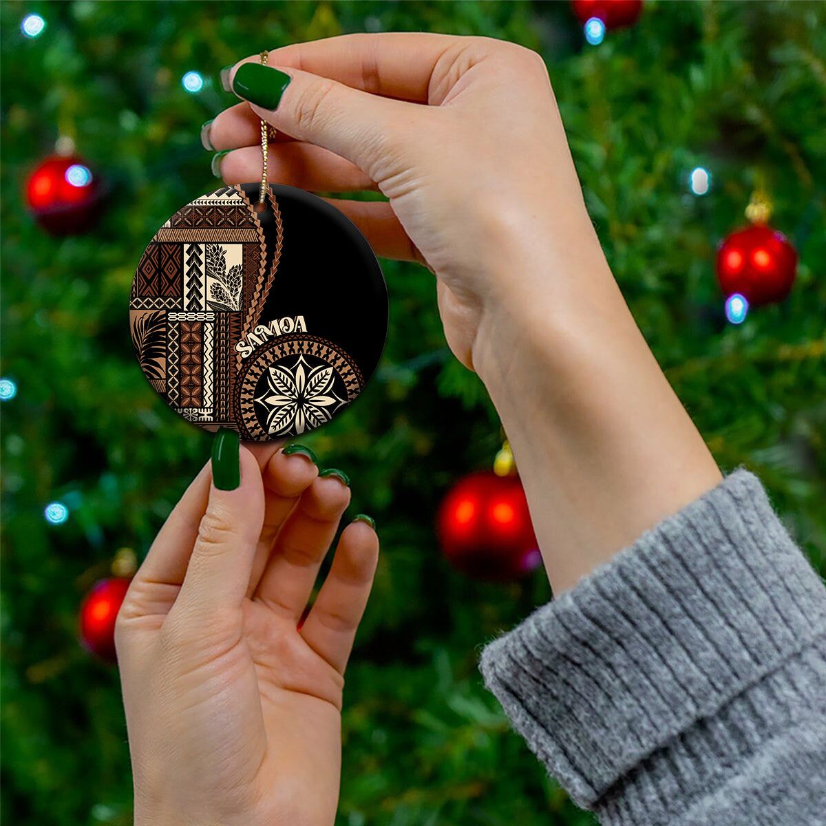 Round ceramic Samoa motif ornament in hand, black and tan pattern with gold hanging loop
