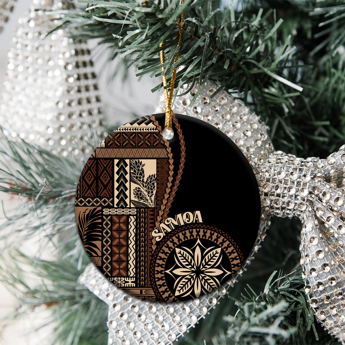 Round black ceramic Samoa motif ornament with tan pattern and gold hanging loop on tree