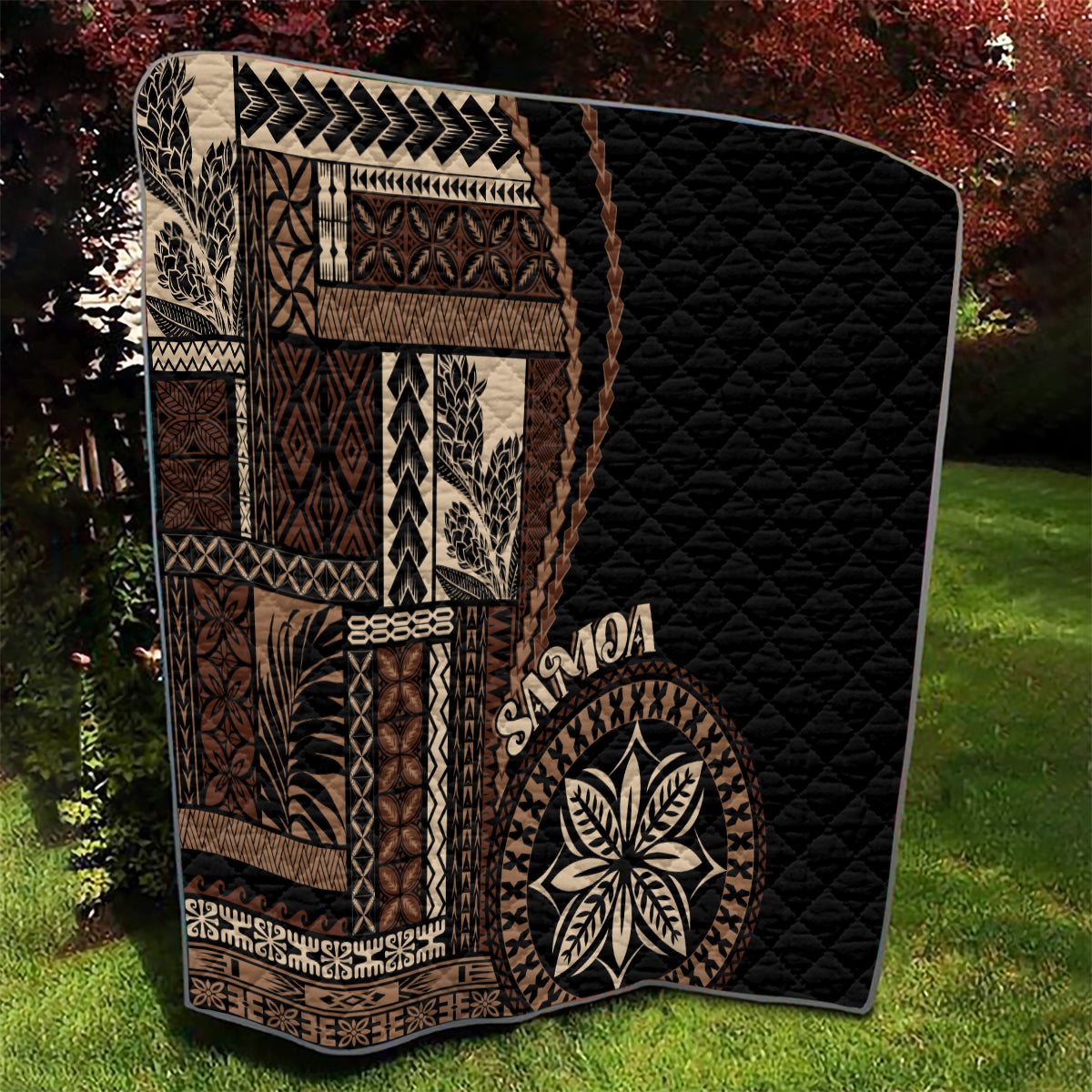 Black Samoa siapo motif quilt blanket with tan patterned panels and leaf emblem