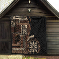 Black Samoa siapo motif quilt blanket with tan geometric panels and leaf emblem on porch