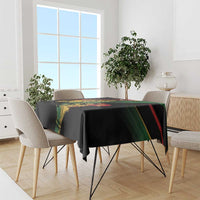 Reggae-themed tablecloth draped over dining table: black with colorful print and green/red stripe border