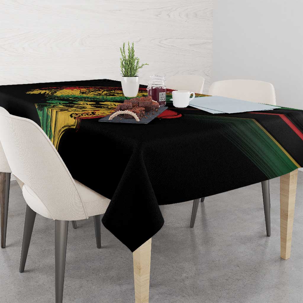 Black reggae print tablecloth with green and red striped trim, neatly draped over table
