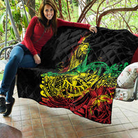 Black diamond-quilted quilt with colorful reggae dancer design, spread out on a patio.