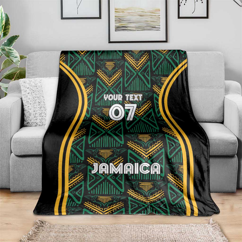 Jamaica reggae blanket draped on sofa, teal and gold ethnic pattern on black