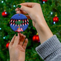 Blue round ceramic Christmas ornament with gold hanger held in hand on a tree
