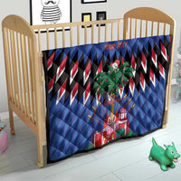 Blue quilt on a wooden crib with zigzag stripes, palm tree art, and Christmas gifts