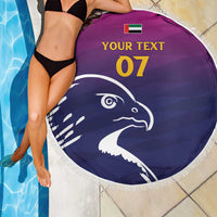 Round beach blanket partially shown with purple/navy falcon print, white fringe, custom text 07