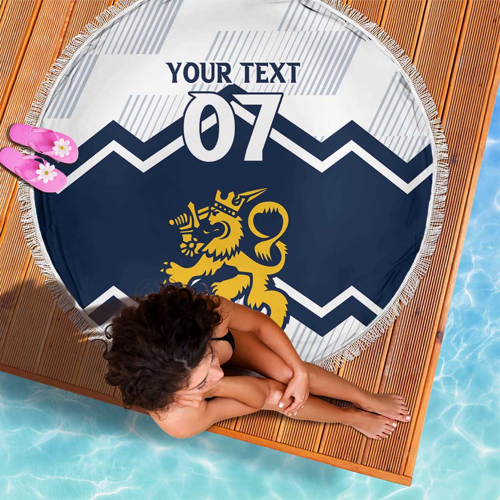 Round beach blanket on wooden deck: white and blue chevrons, lion emblem, fringe