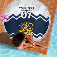 Round beach blanket on wooden deck: white and blue chevrons, lion emblem, fringe