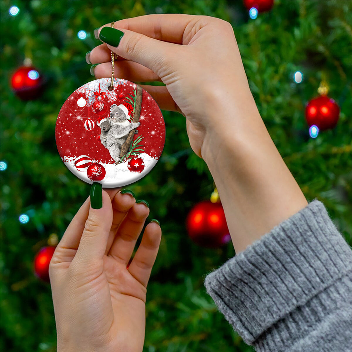 Red ceramic round koala Santa ornament held by hand with gold hanging loop