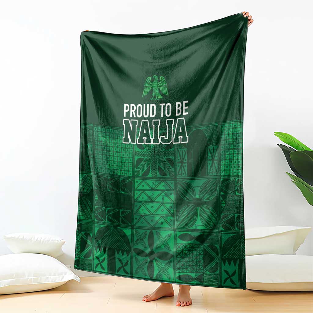 Dark green adire-pattern blanket draped with 'Proud to be Naija' graphic in geometric blocks