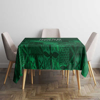 Dark green tablecloth with geometric adire patterns, square table setting