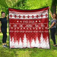 Red and white Christmas quilt spread outdoors with 'HYVAA JOULUA' and fir tree print