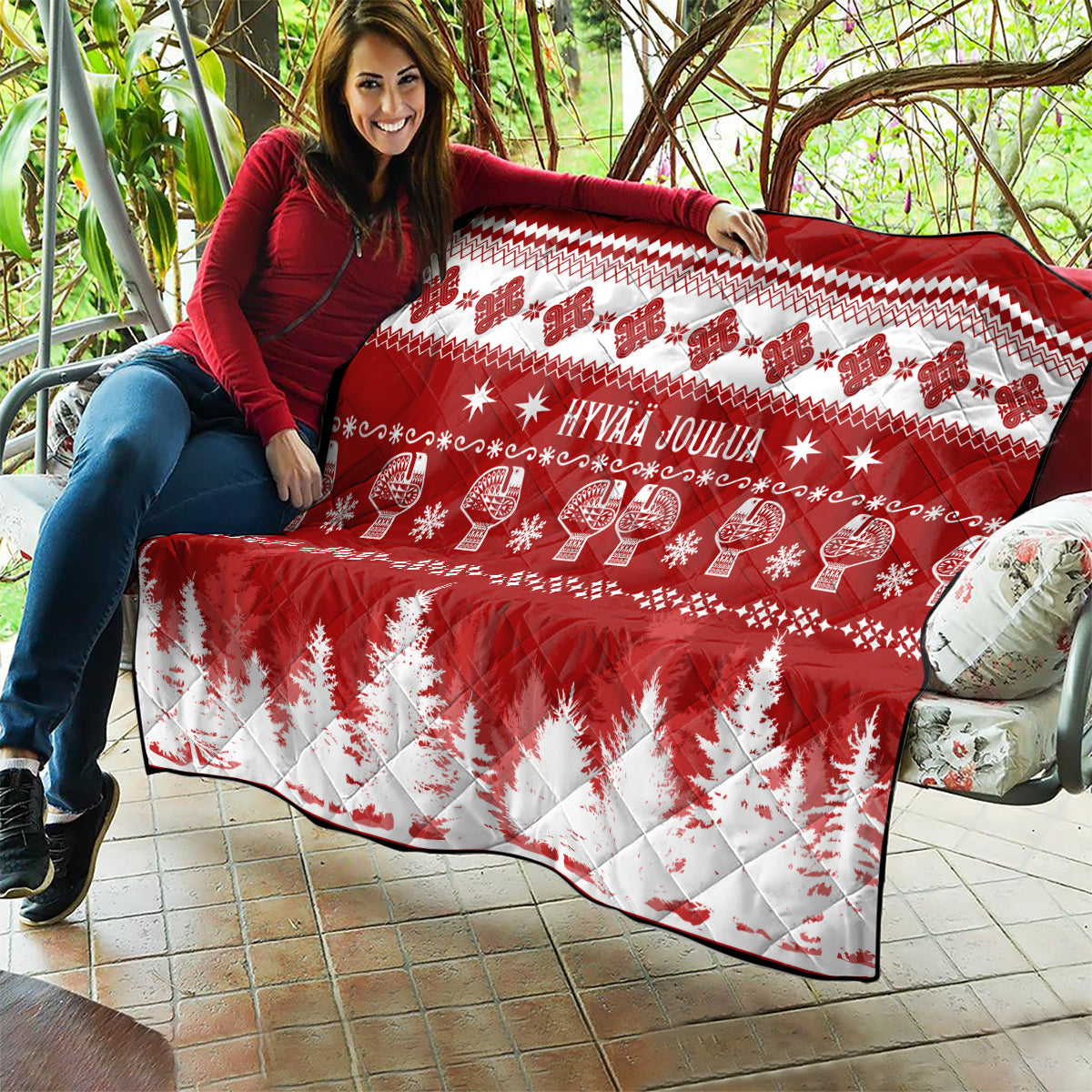 Red and white Christmas quilt draped over couch, 'HYVAA JOULUA' and fir tree print