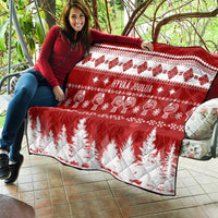 Red and white Christmas quilt draped over couch, 'HYVAA JOULUA' and fir tree print