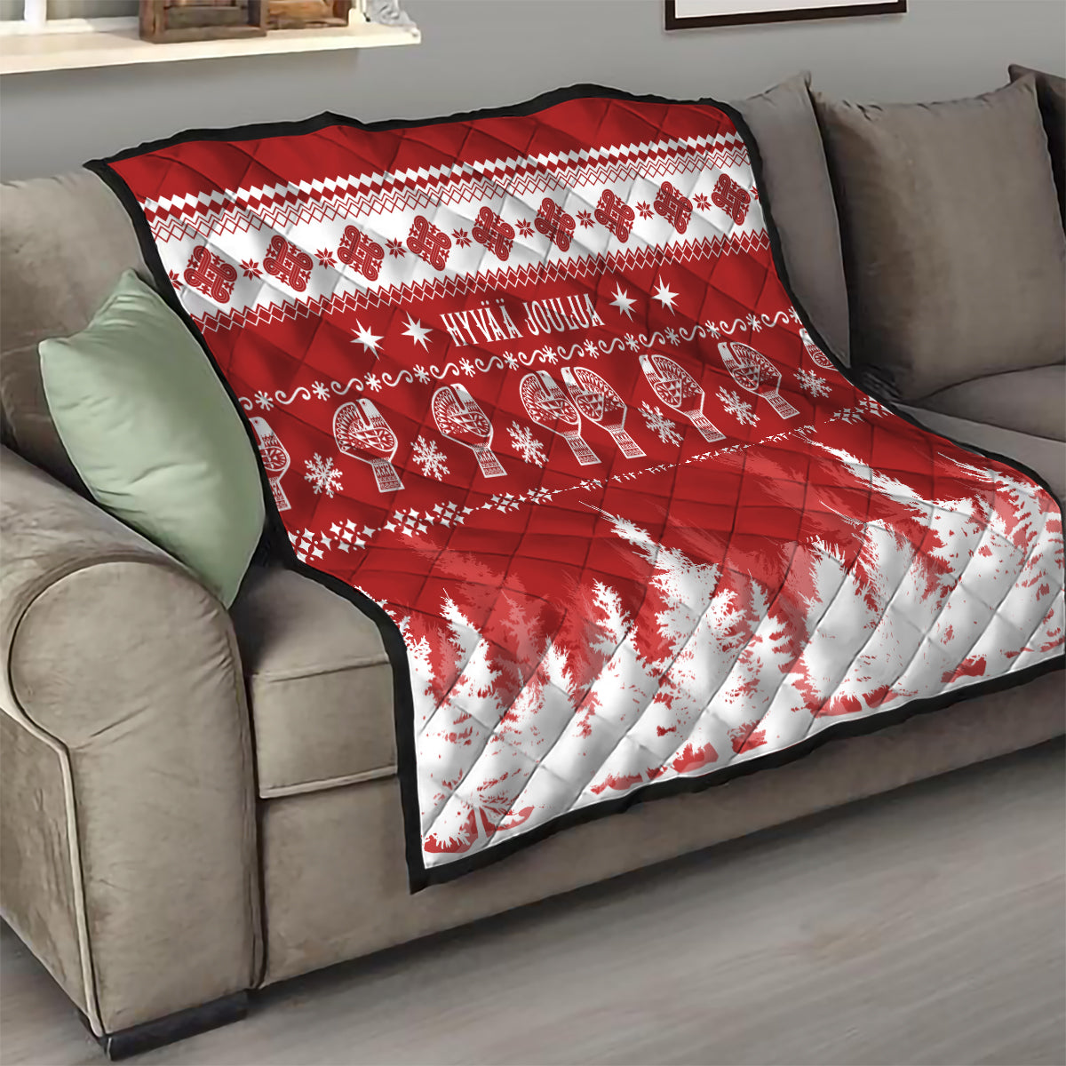 Red and white Christmas quilt on sofa with 'HYVAA JOULUA' text and snowy pine pattern