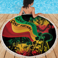 Round beach blanket with One Love One Heart reggae print on deck by pool