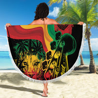 Round beach blanket with One Love One Heart reggae print held up on sandy beach