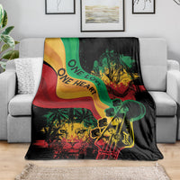 Reggae-themed throw blanket on gray sofa, black with green red yellow lion and guitar artwork.
