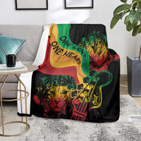 Reggae-themed throw blanket draped on gray chair, black with green red yellow lion and guitar design.