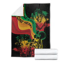 Reggae-themed throw blanket folded and rolled, black with colorful lion guitar and “One Love” text.