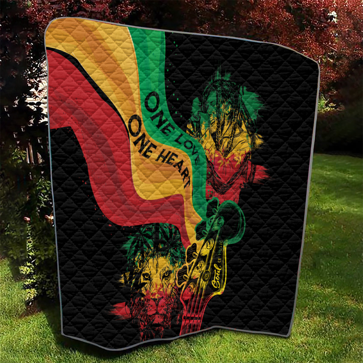Black quilt blanket featuring colorful reggae heart, lion and guitar artwork, quilted texture.