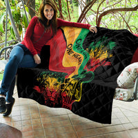 Black quilt with colorful reggae heart, lion and guitar graphic, spread across couch seating.