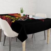 Black tablecloth with colorful reggae artwork and neatly draped corners on a dining table